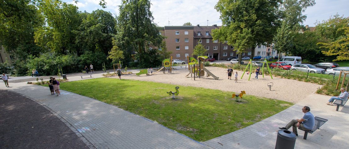 Spielplatz für Kleinkinder unter Bäumen, in der Nähe mehrgeschossigen Wohnhäuser 